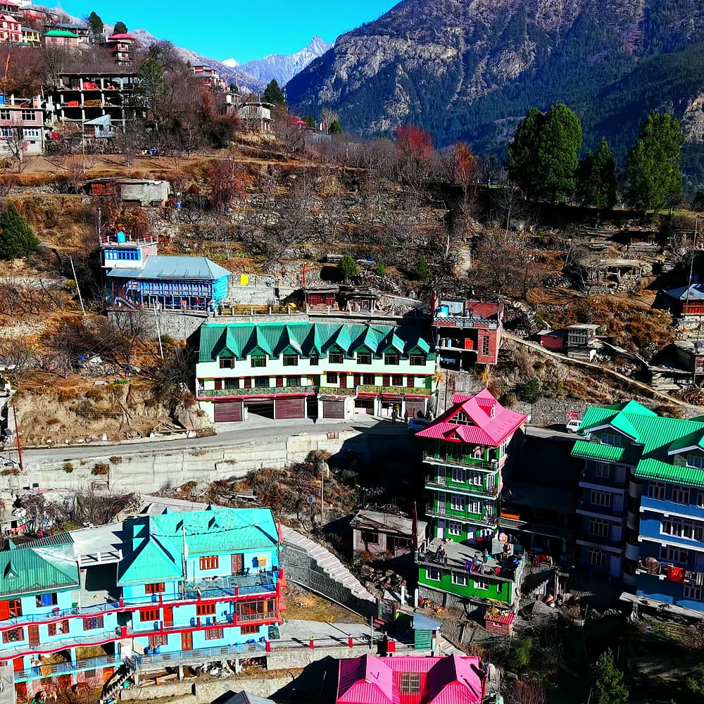Aerial view of colourful mountain homes and green-roofed buildings on a hillside