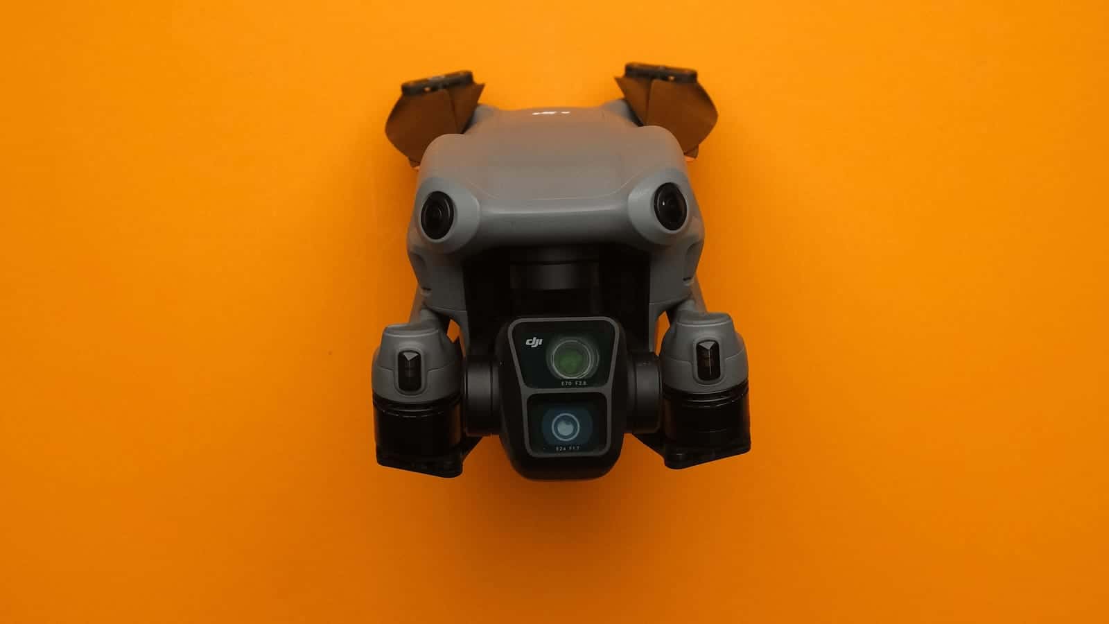 A grey camera drone seen from above on an orange background