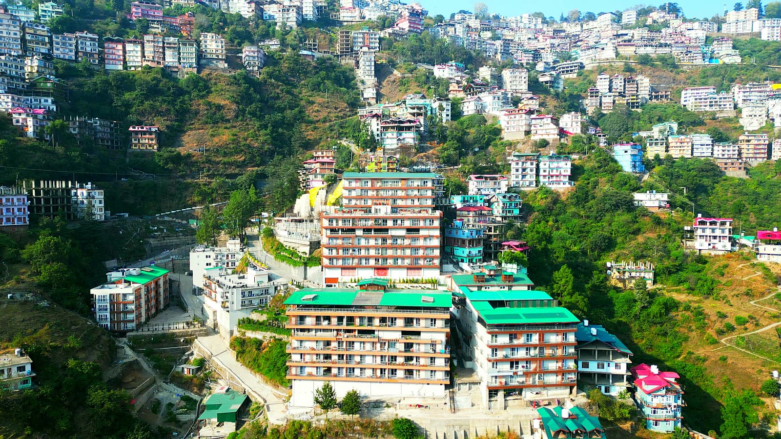 Aerial view of the Flexigo Stays building with green roofs, set against a hillside covered in houses